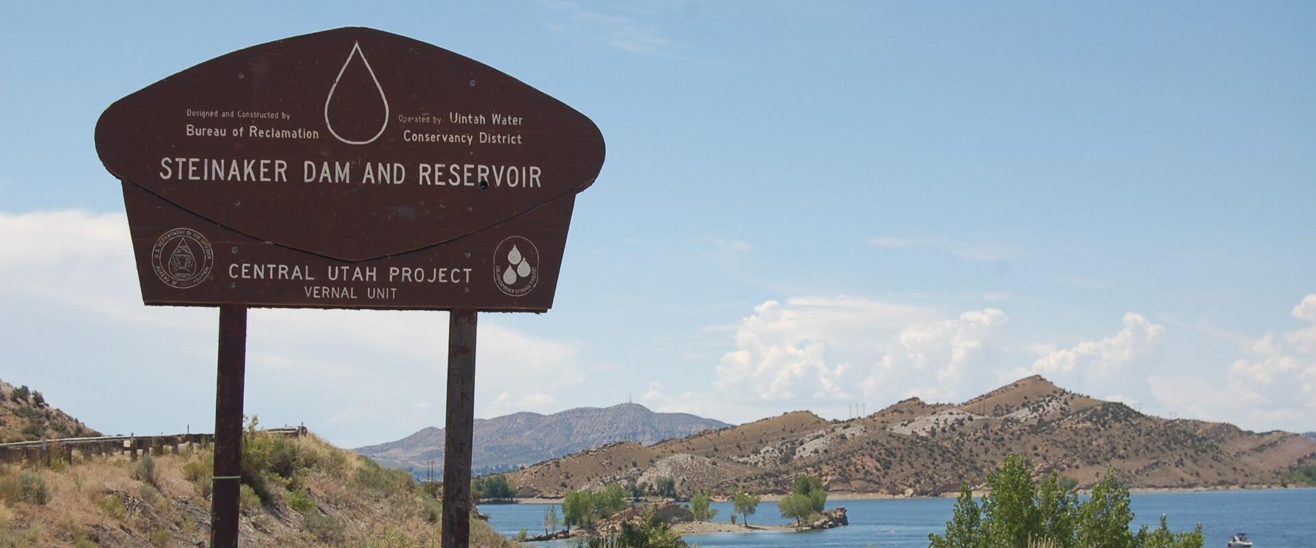 Steinaker Dam and Reservoir entrance sign with the reservoir and hills beyond