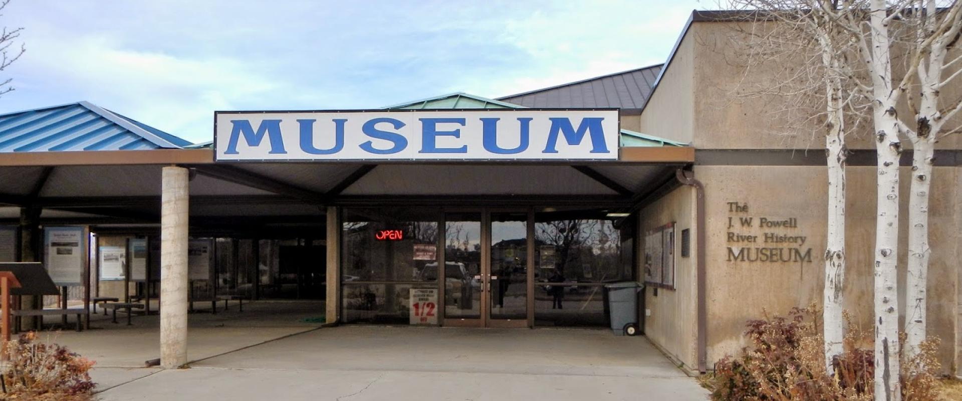The image shows the exterior entrance of a building with a large sign reading "MUSEUM" above the entrance, and the text "The J. W. Powell River History MUSEUM" is clearly visible on the wall to the right.