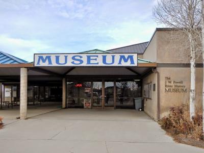 The image shows the exterior entrance of a building with a large sign reading "MUSEUM" above the entrance, and the text "The J. W. Powell River History MUSEUM" is clearly visible on the wall to the right.