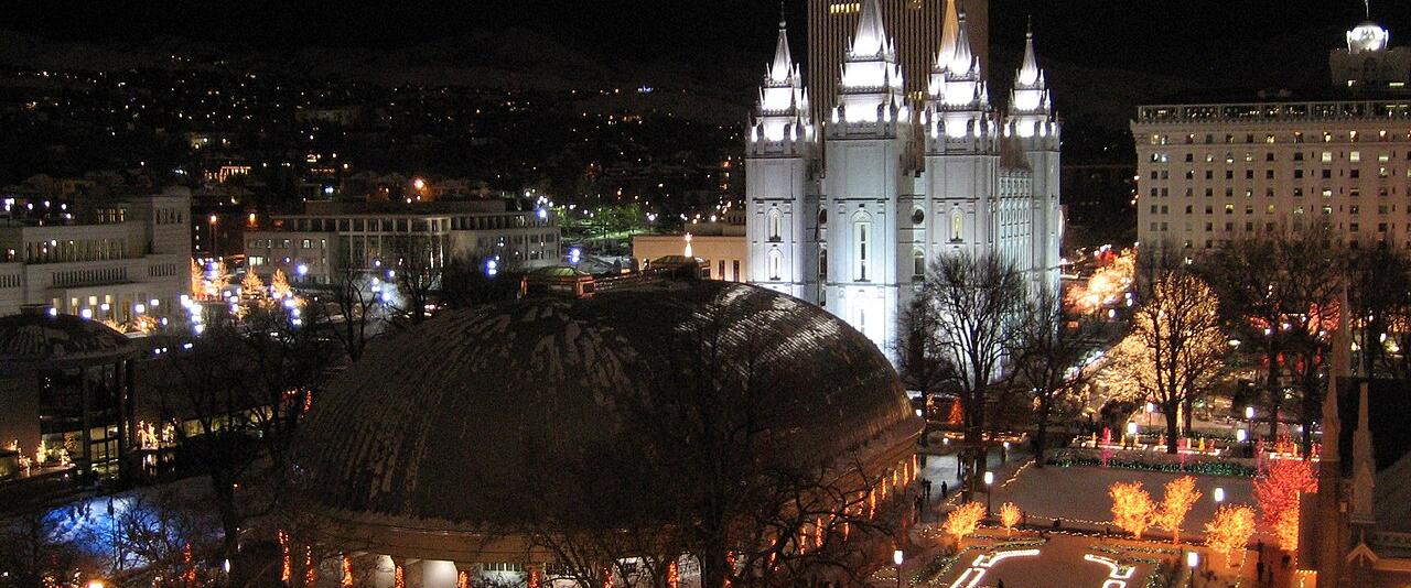 Temple Square in Salt Lake City lit for Christmas at night, with the Tabernacle dome and the Salt Lake Temple