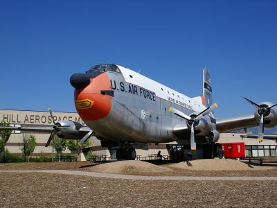 A Douglas C-124 Globemaster II aircraft displayed outdoors on a gravel pad with a building in the background.