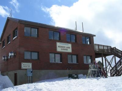A two-story brick building with a sign reading "Powder Mountain Hidden Lake Lodge" and a smaller sign for "Restrooms / First Aid"